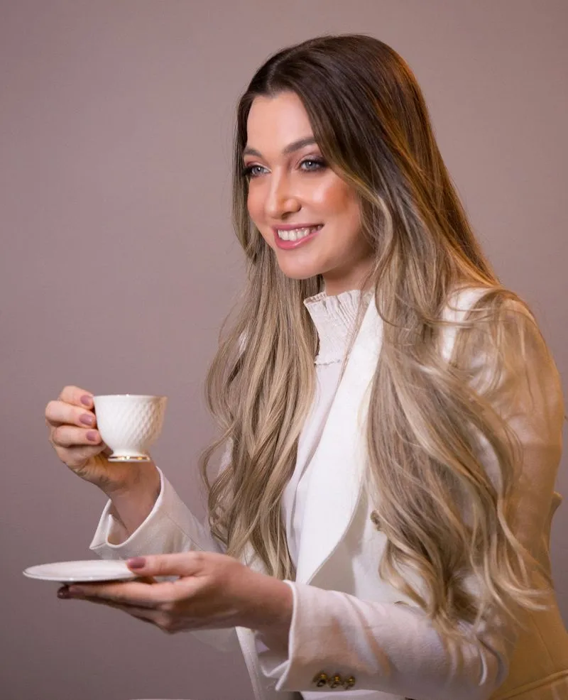 Drielle Alvarenga sorrindo com uma xícara de chá